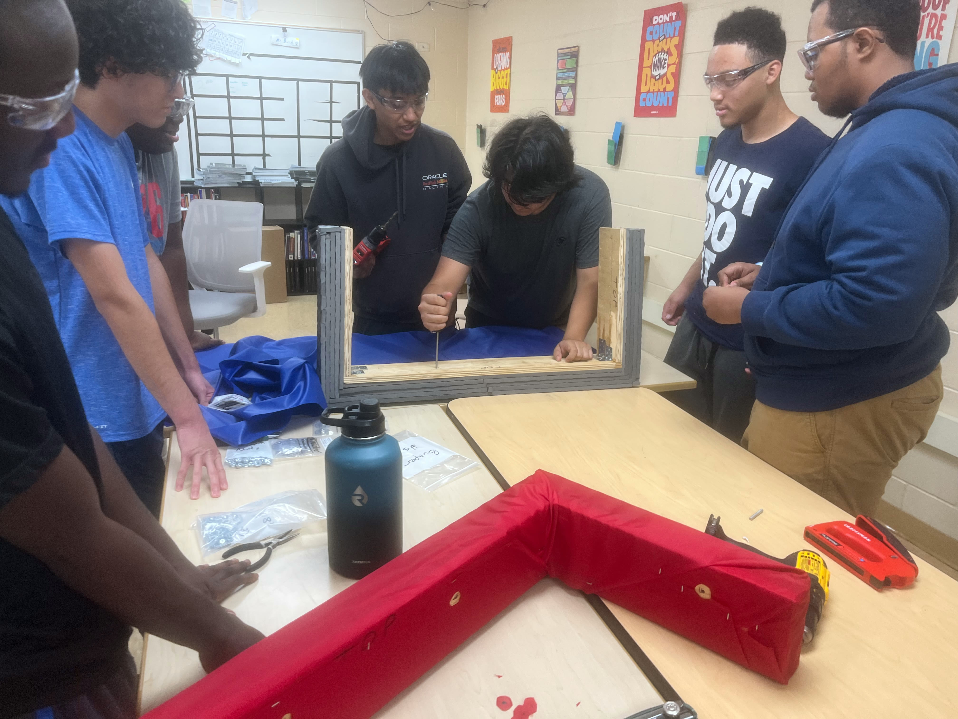 Team 2151 students building a robot together at a worktable